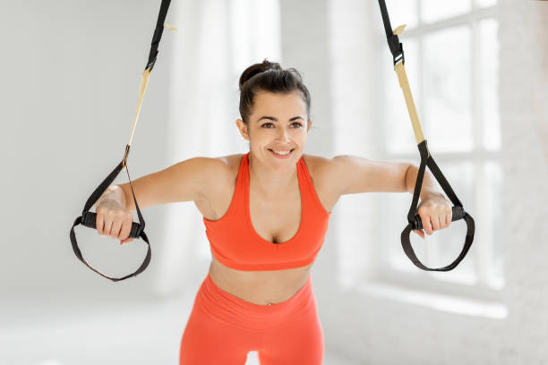 istock Athletic woman squeezing with suspension straps at gym 1325708818
