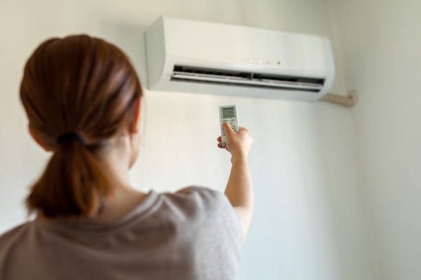 istock Woman turning on air conditioner with remote 1325708864