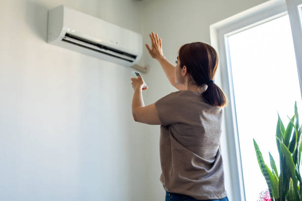 mujer encendiendo el aire acondicionado - air condition fotografías e imágenes de stock