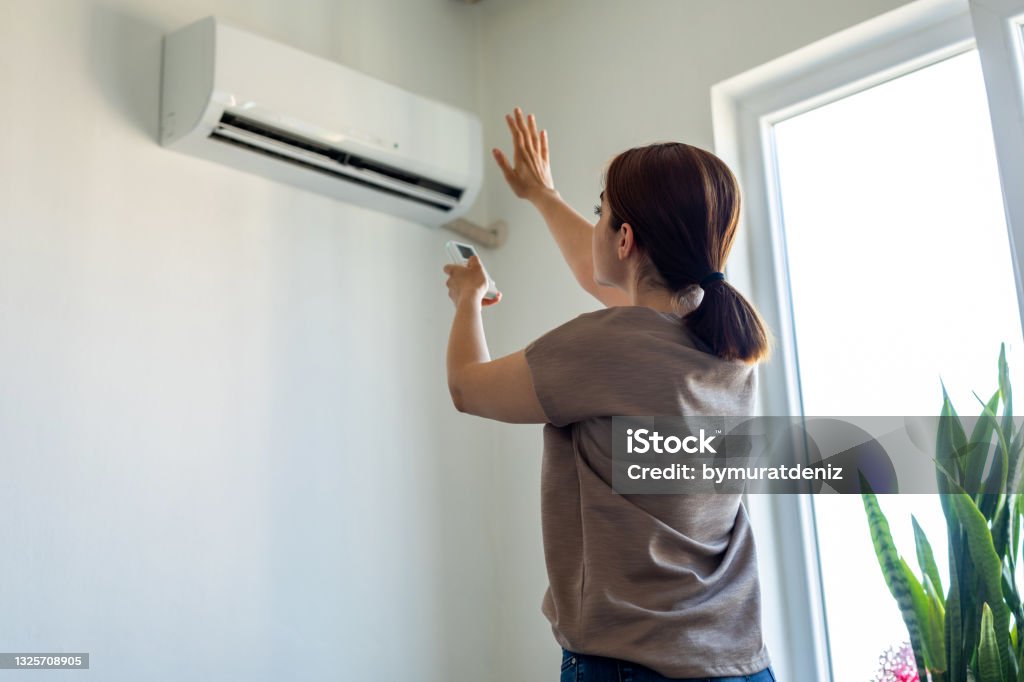 Woman turning on air conditioner Air Conditioner Stock Photo
