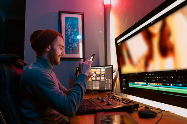 istock Male Video Editor sitting at his Computer using phone 1325709057