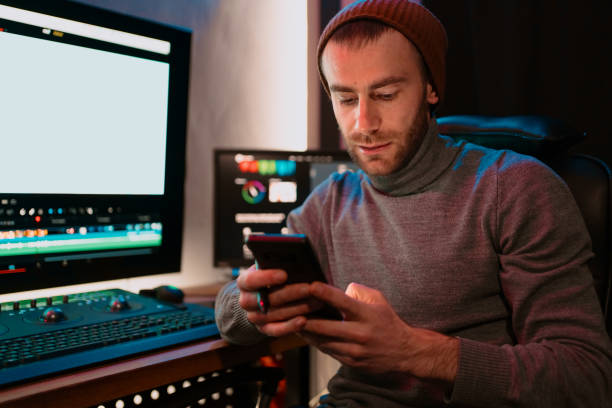 istock Male Video Editor sitting at his Computer using phone 1325709147