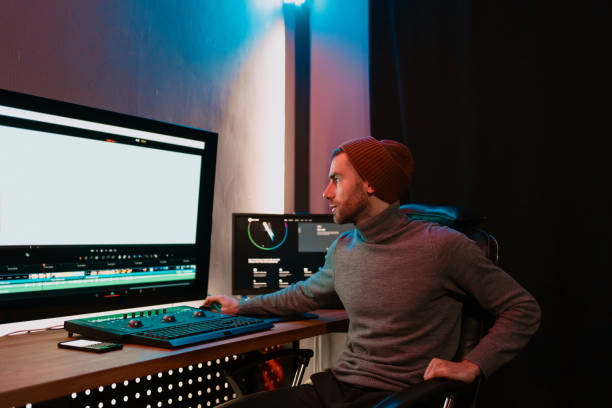 éditeur vidéo masculin travaillant sur son ordinateur personnel avec un grand écran vide - studio de post production photos et images de collection