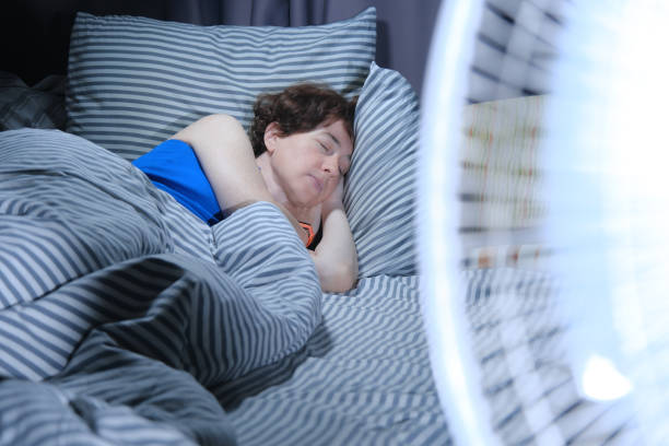 istock Woman is sleeping in bed while electric fan is blowing on the foreground 1325709270