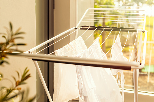 Hanging laundry on balcony on the drying rack opposite sea and palm trees view at sunset sunshine