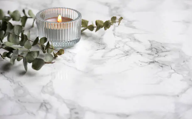 A small candle in glass holder on a marble background with room for your text.