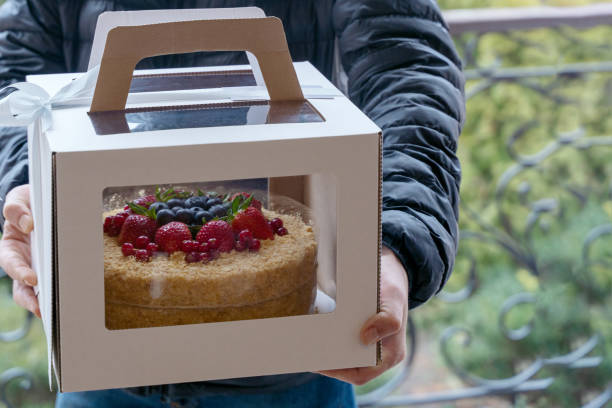 human hands holding cardboard box with holiday cake decorated of berries. - fruit front view isolated berry fruit imagens e fotografias de stock