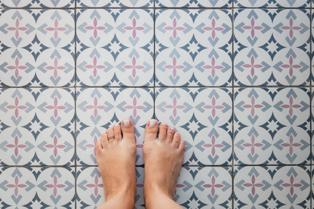 istock Young female bare feet with a ring on a toe on a light tile with a Turkish - Moroccan pattern. View from above. Copy space 1325721755