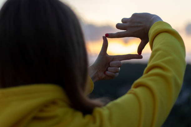 a woman looks at the sunset. - imagination creativity finger frame frame imagens e fotografias de stock