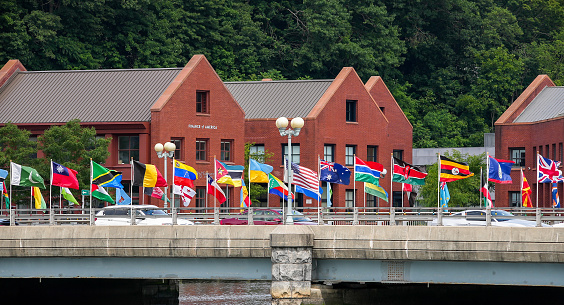 Westport, CT, USA - June 26, 2021: Flags waving on bridge over Saugatuck river in nice cloudy day