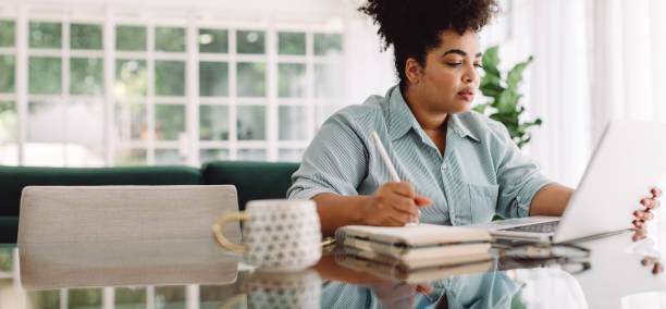 istock Businesswoman taking notes and using laptop at home 1325729268