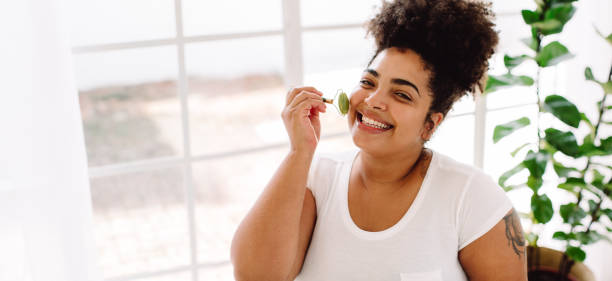 istock Pretty woman using massage roller on facial skin 1325729272