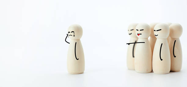 Wooden dolls in concept of being harassed, slander and bullied by society. Photographs of the Wooden dolls standing apart from the group and there are illustrations drawings showing the emotion of crying because of being bullied. The concept of being harassed and slander. slander stock pictures, royalty-free photos & images