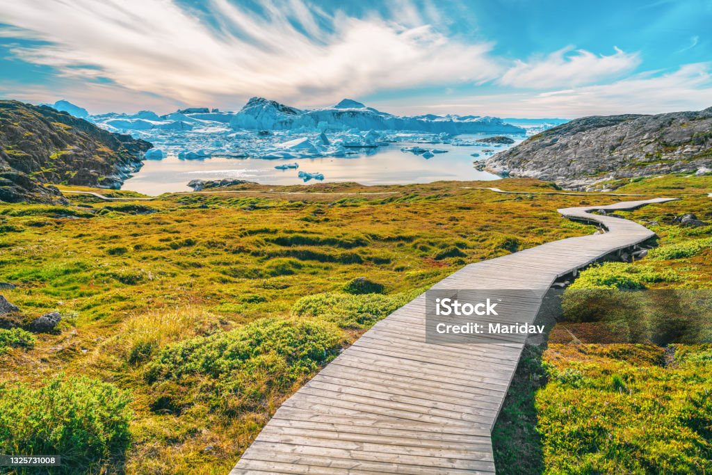 Hiking trail path in Greenland arctic nature landscape with icebergs in Ilulissat icefjord Hiking trail path in Greenland arctic nature landscape with icebergs in Ilulissat icefjord. Photo of scenery ice and iceberg in Greenland in summer. Greenland Stock Photo