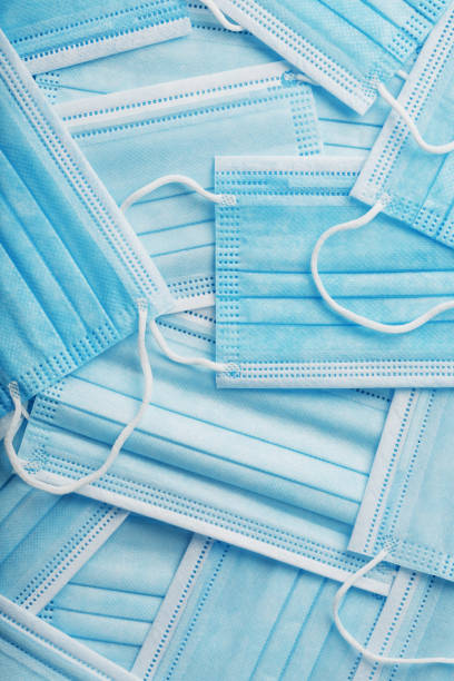istock Blue medical protective masks are scattered as a background, texture. 1325731490