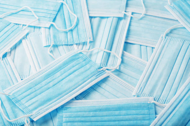 istock Blue medical protective masks are scattered as a background, texture. 1325732303