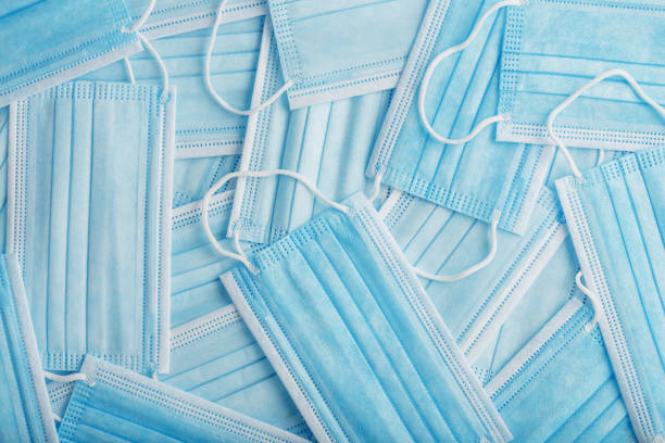 istock Blue medical protective masks are scattered as a background, texture. 1325732355