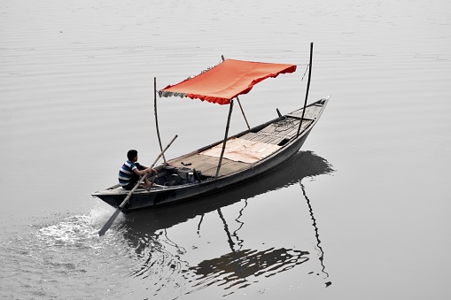 Rajshahi, Bangladesh December 25, 2016 Poor man sailing a traditional boat in a river