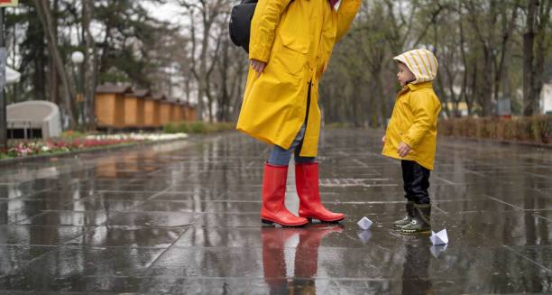 istock Child playing with paper boats in water puddle 1325737192