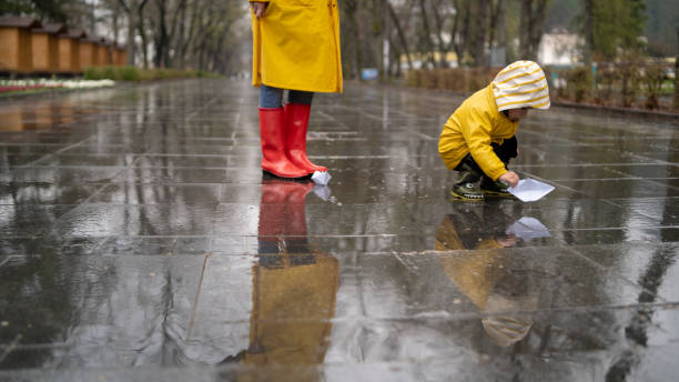 istock Child playing with paper boats in water puddle 1325737208