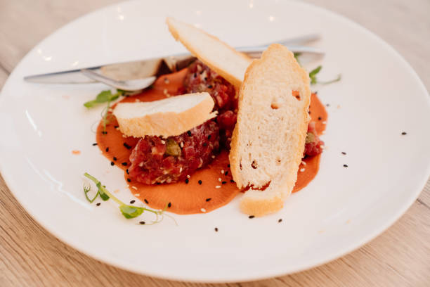 istock tartare with sauce, microgreen and bread on a white plate. 1325739952