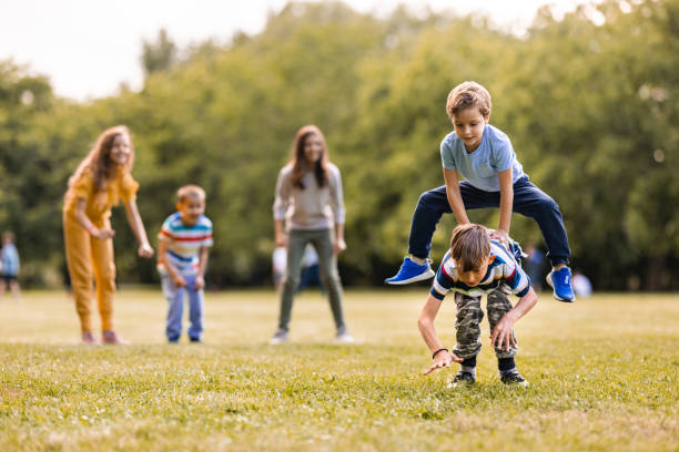 Happy kids having fun while playing leapfrog game in public park