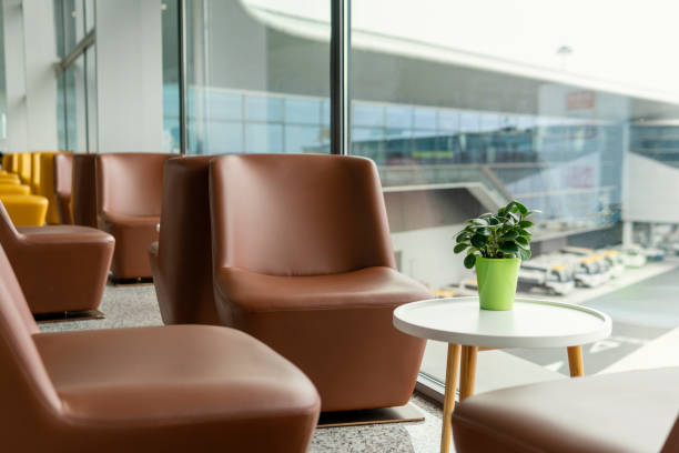 an asian chinese tourist at airport waiting lounge looking at his smart phone sitting while waiting for check-in