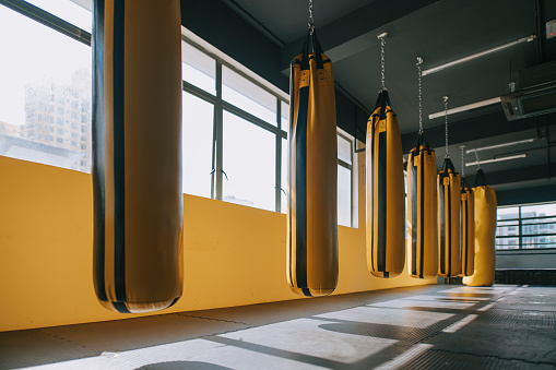 Gym health club with a row of yellow punching bag sandbag beside window day time