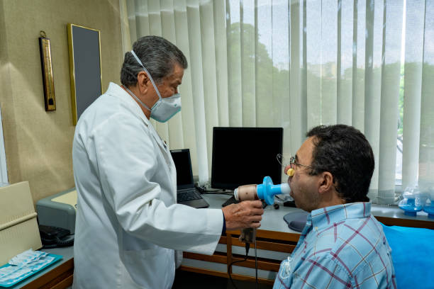 Mature man performing pulmonary function test and spirometry at doctor office stock photo