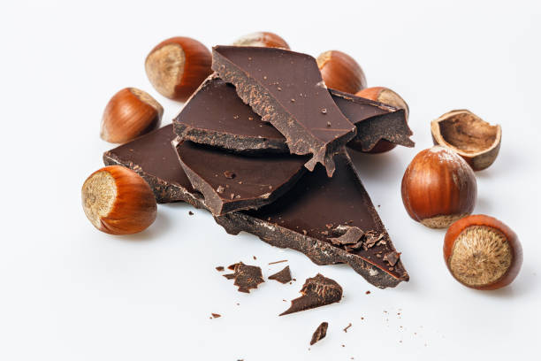 istock Ripe wild hazelnuts and bitter chocolate. Nuts and and stack of a dark chocolate on a white background. Natural organic products. Copy space. Food still life 1325755158