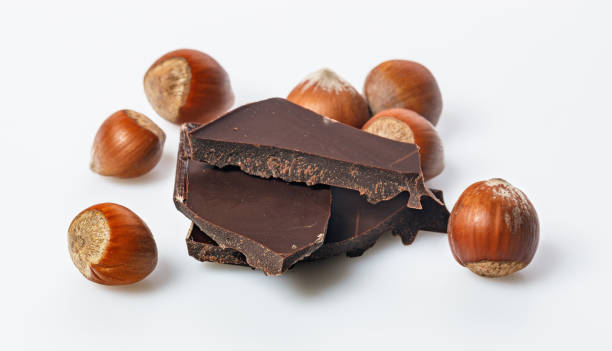 istock Ripe wild hazelnuts and bitter chocolate. Nuts and and stack of a dark chocolate on a white background. Natural organic products. Copy space. Food banner format 1325755229