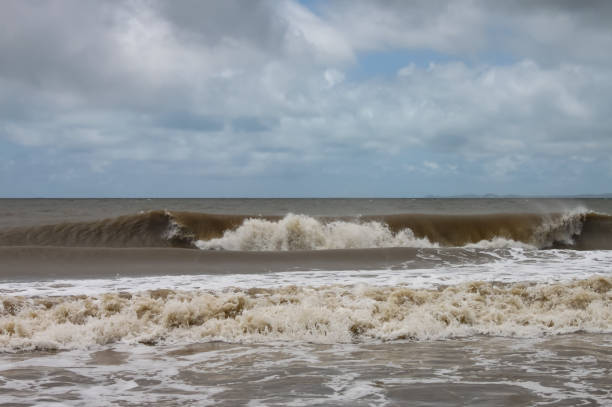 Chocolate brown waves roll toward the shore under a stormy sky after a hurricane