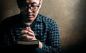 istock Christian life crisis prayer to god. Man Pray for god blessing to wishing have a better life. man hands praying to god with the bible. believe in goodness. Holding hands in prayer, eyes closed. 1325758060