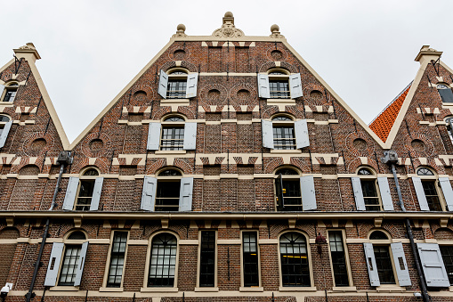 Side view of a series of different townhouses and apartment buildings along the side of a canal in the historic centre of Amsterdam.