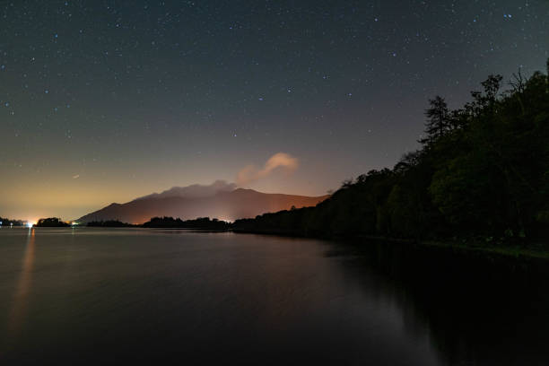 una vista del cielo nocturno sobre el agua de derwent en el distrito de los lagos inglés con el resplandor naranja de keswick - horizon over water england uk summer fotografías e imágenes de stock