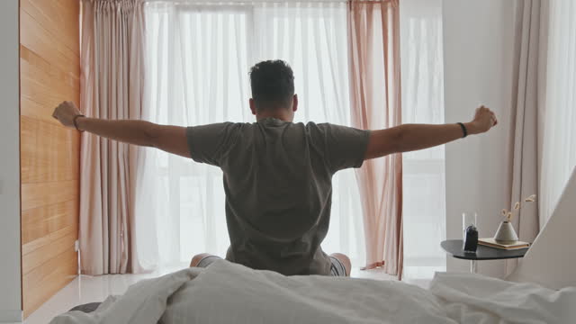 Latin Man Stretching In Bed After Sleep