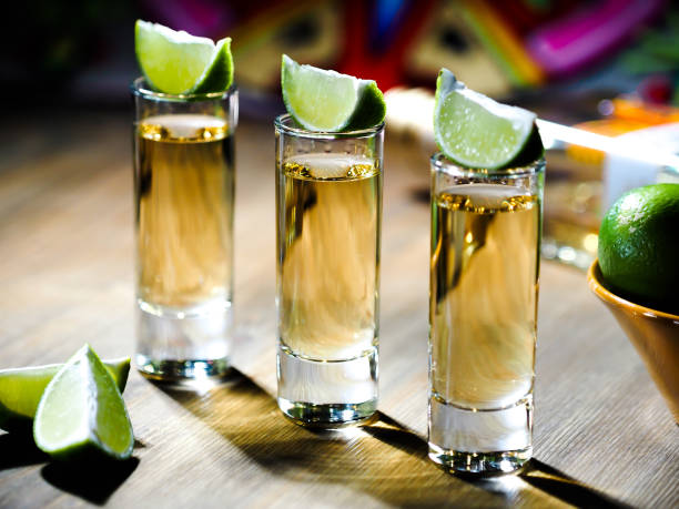 Three shots of tequila in tall shot glasses Three shots of tequila in tall shot glasses with lime wedges on top tequila drink photos stock pictures, royalty-free photos & images