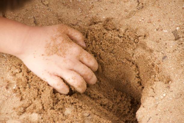 istock Male asian child hand playing with beach sand 1325764784