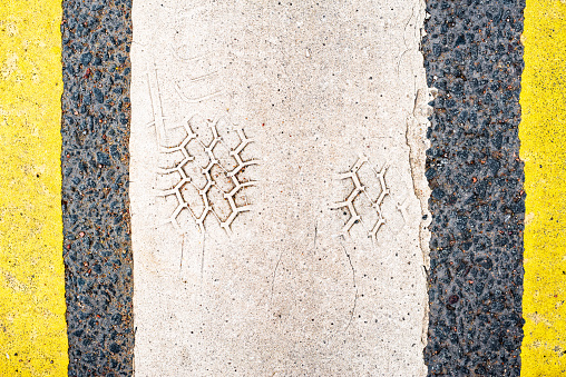 Old asphalt on the road. Vertical shabby markings at the pedestrian crossing. Traces of car tires. City environment. Top view close up.