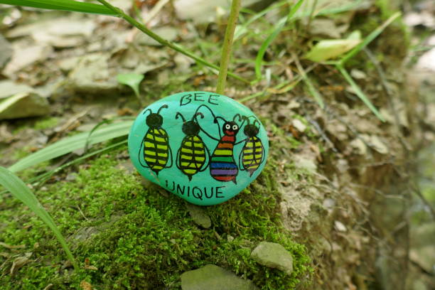 Bee unique message painted on kindness rock laying on mossy ground