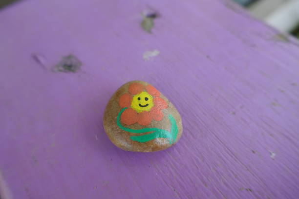 Smiling happy flower painted onto kindness rock