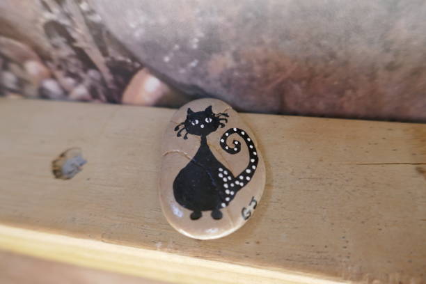 Black cat cartoon painted onto kindness rock