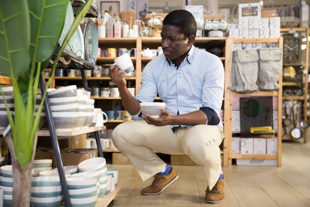 istock Man carefully chooses ceramic mugs in store 1325767526