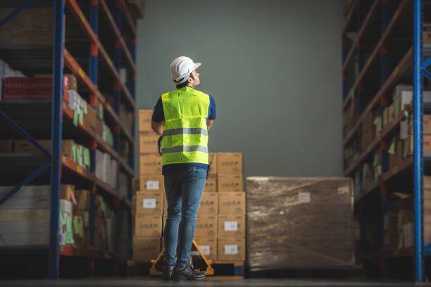 A man woker using forklift in warehouse, foreman wearing helmet and safety vest in storehouse, manager checking stock, warehouse full of shelves, Forklift Working in Logistics Storehouse, forklift loader. un hombre woker usando carretilla elevadora en almacén, capataz con casco y chaleco de seguridad en almacén, gerente de chequeo de stock, almacén lleno de estantes, carretilla elevadora trabajando en almacén de logística, cargador de carretilla elevad