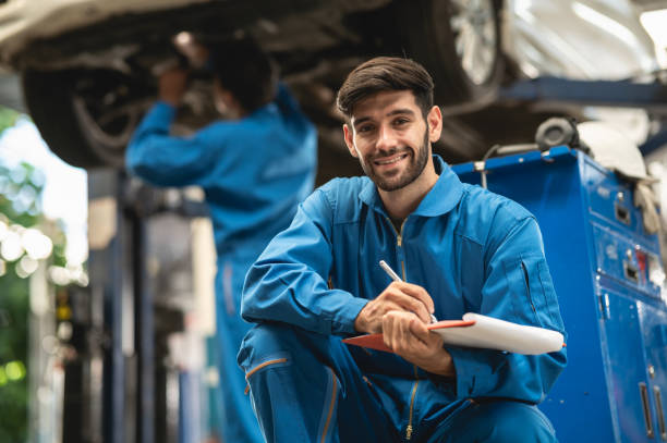 porträt-foto von professionellen aussehen kaukasischen fahrzeug service techniker kniet vor der autowerkstatt und halten auto-inspect checkliste. - automechaniker stock-fotos und bilder