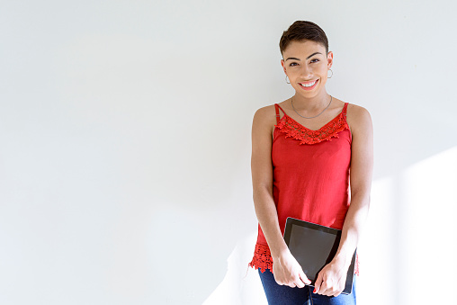 Young woman portrait on light background holding digital tablet.. Study / work at home concept.