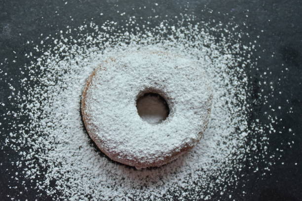 donut and powdered sugar on a black background, donut and powdered sugar on a black background, powdered sugar stock pictures, royalty-free photos & images