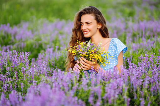 Portrait of beautiful woman in amazing in a blooming field. Nature, vacation, relax and lifestyle. Summer landscape.