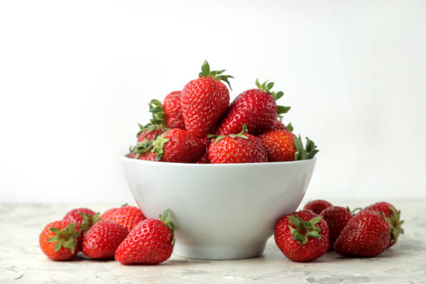 istock Ripe, delicious strawberries. Red strawberry in a ceramic bowl on a light concrete table. 1325776440