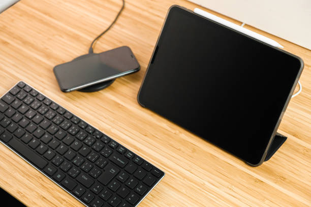 istock Smart phone is charging on wireless charging next to the tablet and keyboard. 1325779377